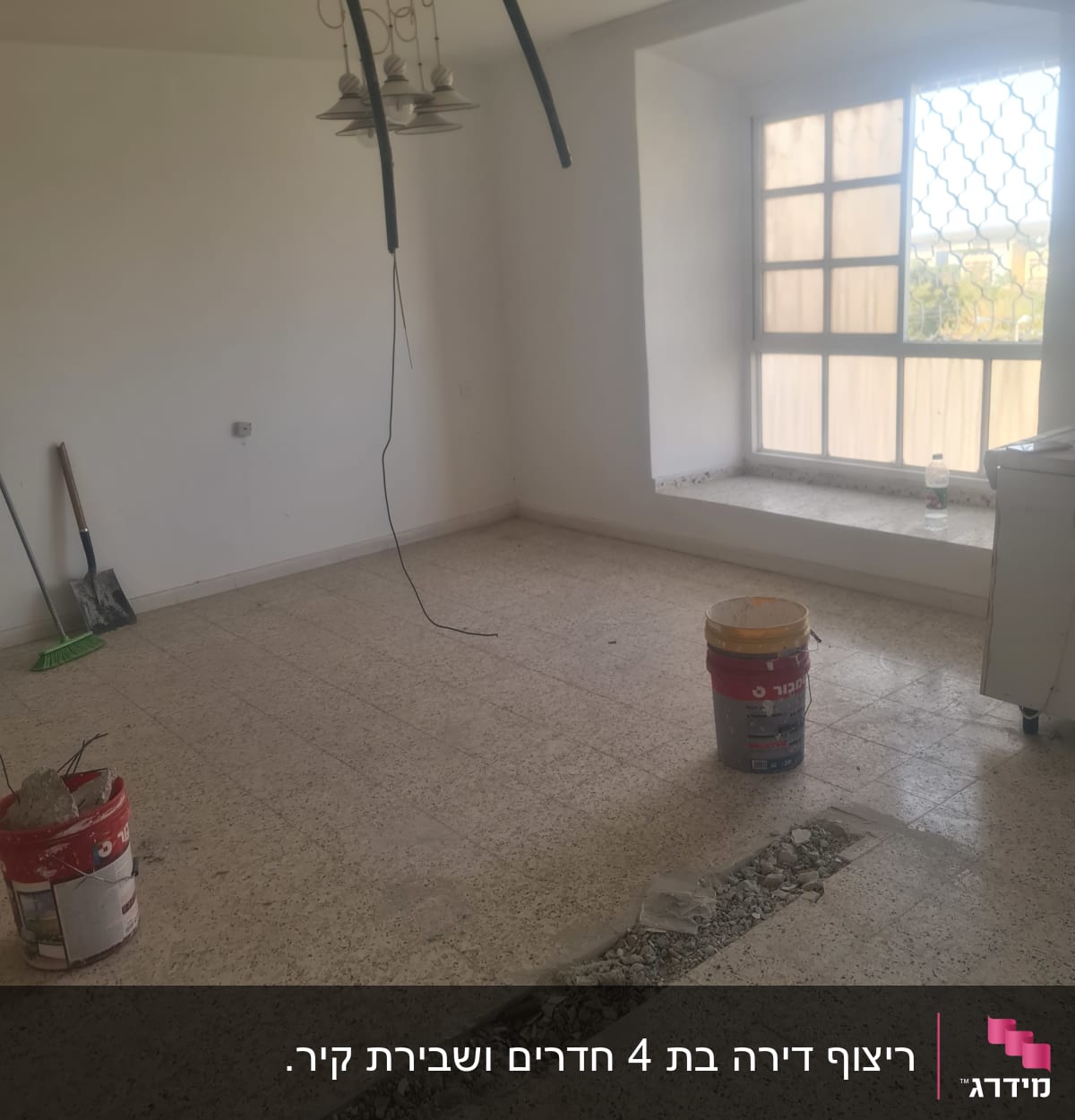 חדר בשיפוץ עם דלי צבע, חוטי חשמל חשופים ורצפה שבורה
